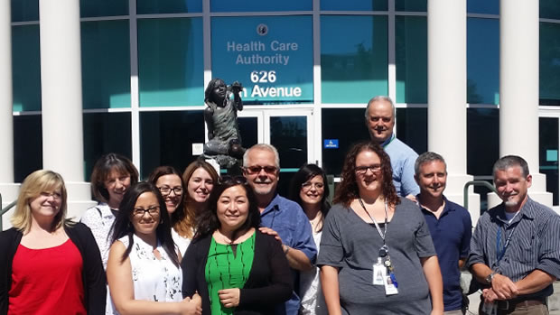 Office of Medicaid Eligibility and Policy (OMEP) staff standing in front of the fountain outside HCA