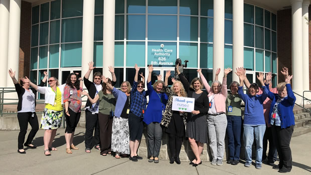 HCA nursing staff group photo in front of the Health Care Authority fountain, waiving and smiling