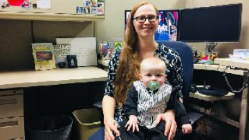 Stefanie Zier at her desk with her son on her lap