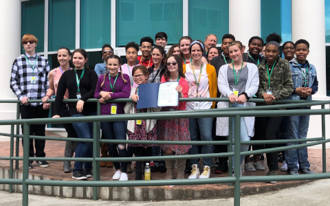 Group of youth with Governor Inslee's mental health proclamation in front of Cherry Street Plaza